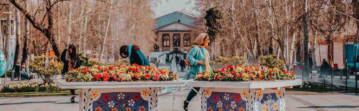 A few female tourists walking on their own in front of Ferdows Garden of Tehran.